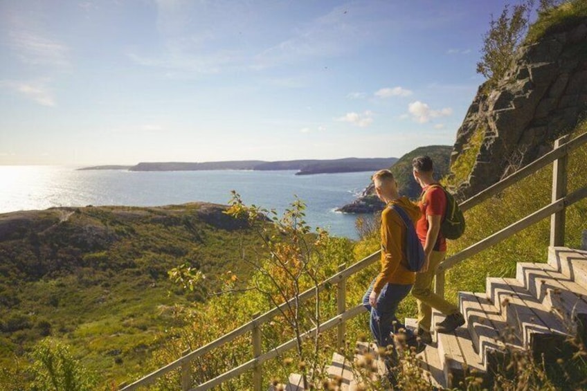 Un paysage côtier avec un escalier menant à un point de vue d’où l’on peut admirer la mer. 1