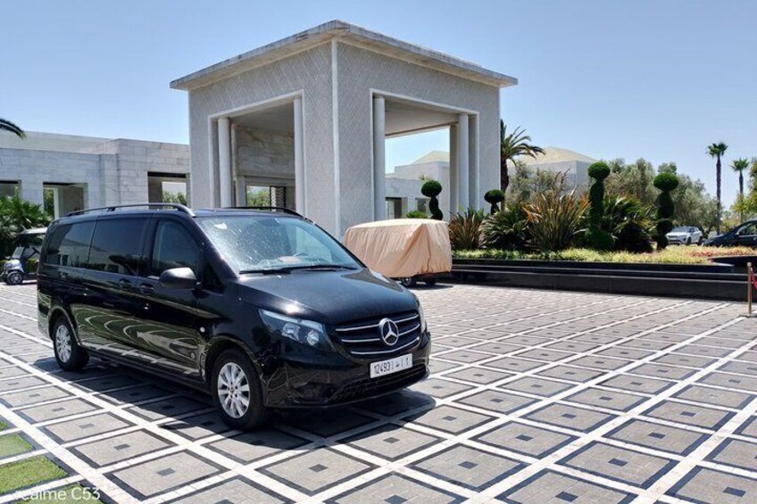 A black Mercedes-Benz C-Class SUV parked in a paved area with a modern building in the background. 2