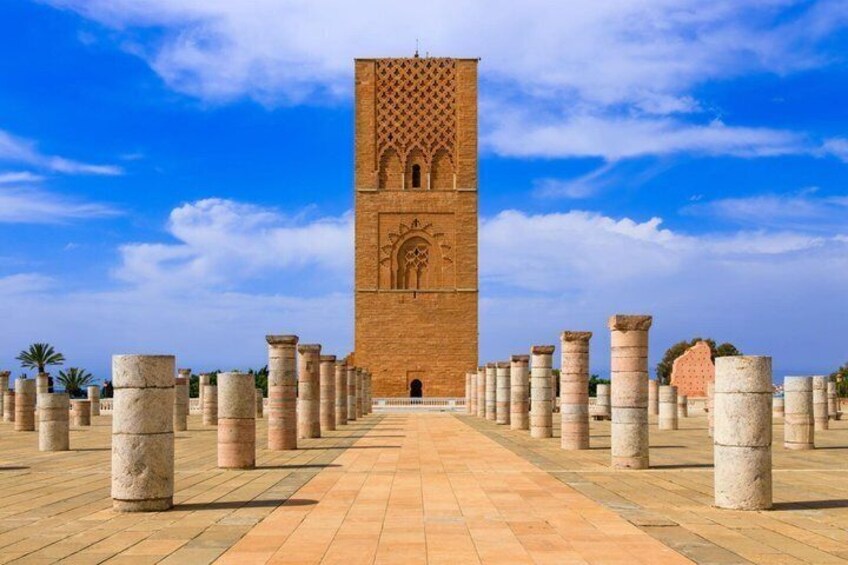 A large, ornate tower with a patterned facade and a series of columns in the foreground. 1