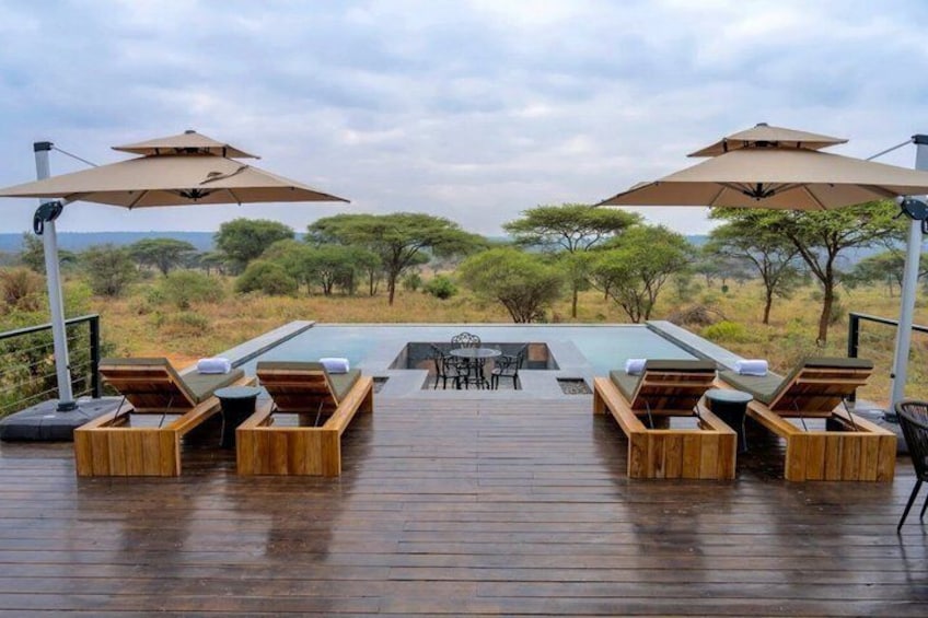A wooden deck with lounge chairs and umbrellas overlooking a pool. 4