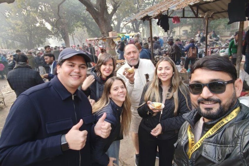 A group of people at an outdoor market with food stalls. 3