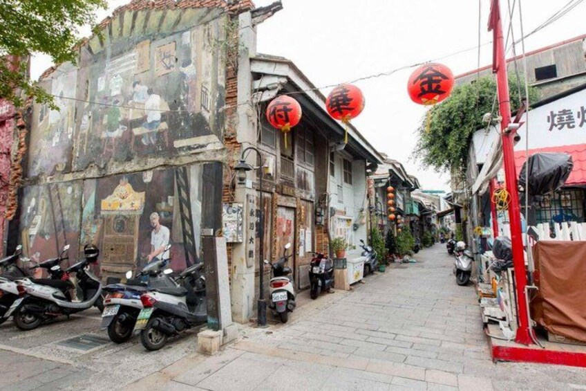 A narrow street with traditional buildings, red lanterns, and parked scooters. 3