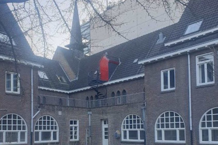 A building with arched windows and a red structure on the roof. 2