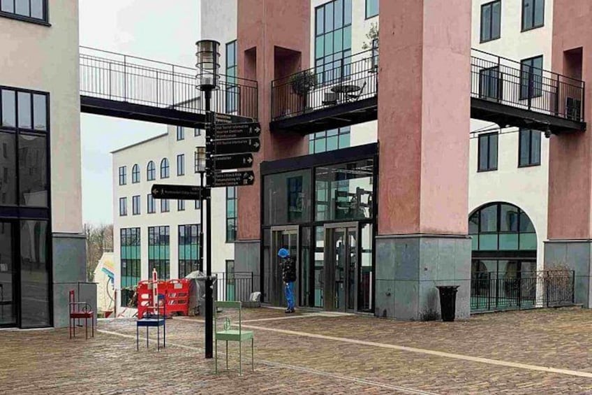 A building with a signpost, red chairs, and a person walking. 3