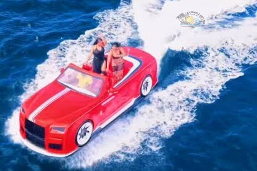 Un auto descapotable rojo avanza a gran velocidad entre las olas del océano. 4