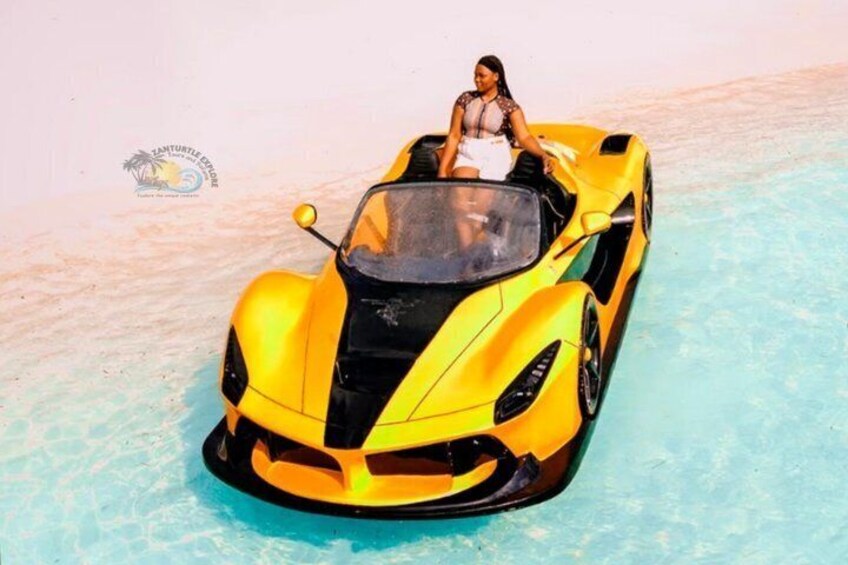Un coche deportivo amarillo sobre una playa arenosa. 2
