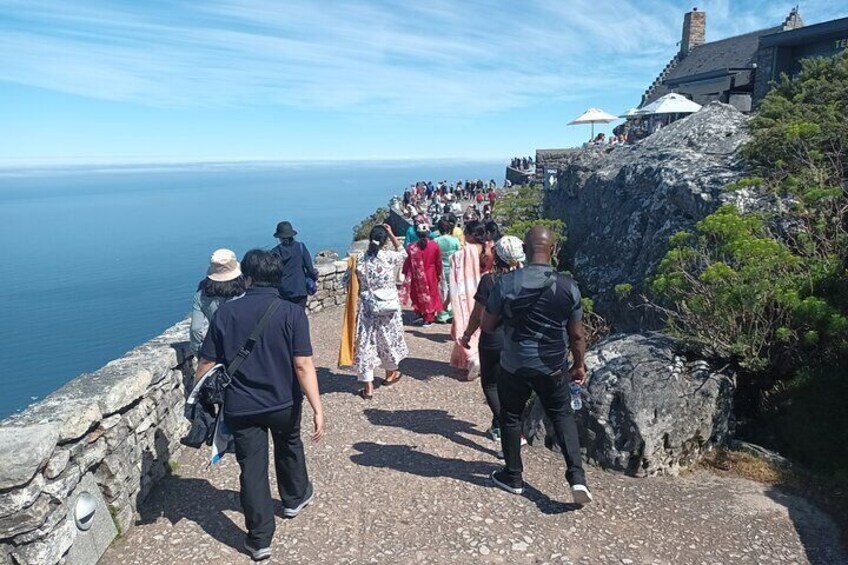 Un gruppo di persone che cammina su un sentiero di pietra lungo il mare. 1