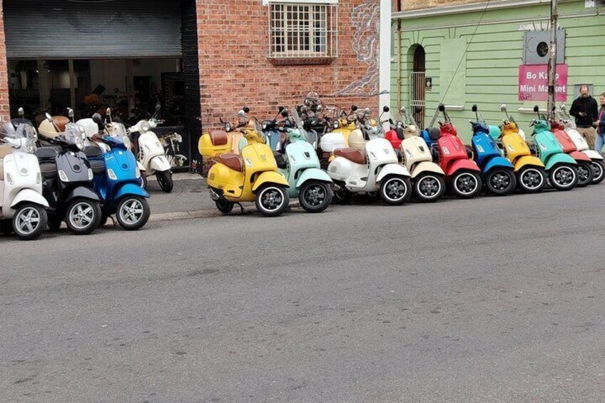 Una fila di scooter colorati parcheggiati di fronte a un edificio con un cartello che riporta 'Bo Ko Mini Market'. 4