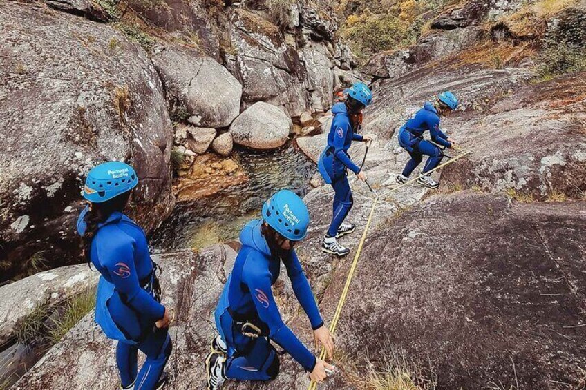 Eine Gruppe von Personen in blauer Kletterausrüstung erklimmt unwegsames Gelände. 5