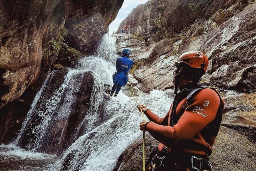 Eine Person seilt sich an einem Wasserfall in einer felsigen Schlucht ab. 1