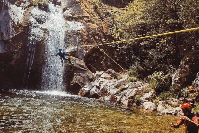 Eine Person lässt sich von einer Klippe mit einem Bungee-Gurt in einen Fluss springen. 4
