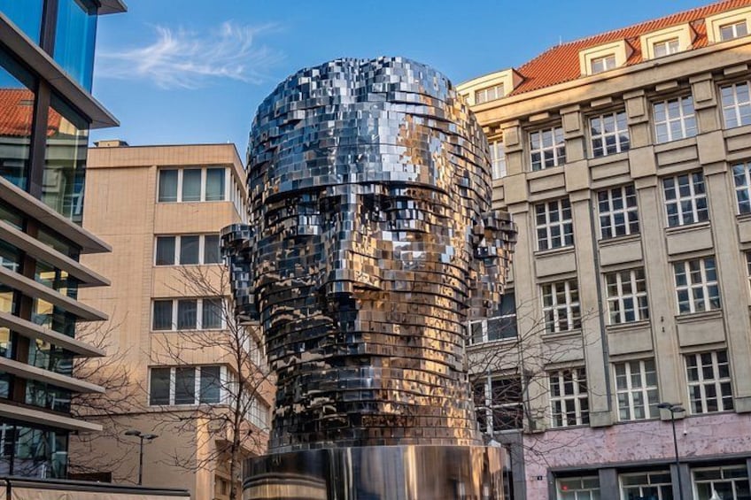 A modern sculpture with a reflective surface, surrounded by buildings. 5