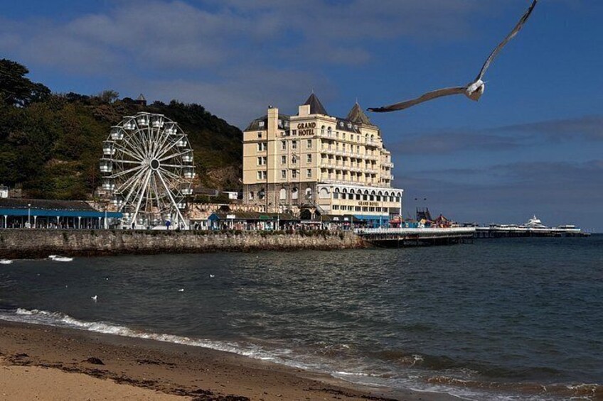 A coastal scene with a large Ferris wheel, a hotel, and a pier extending into the water. 3
