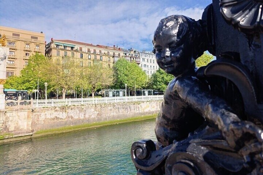 A statue by a river with buildings in the background. 5