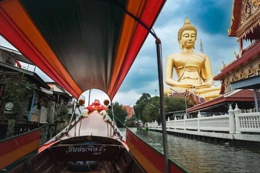 En båt med en stor, gyllene Buddha-staty i bakgrunden. 3