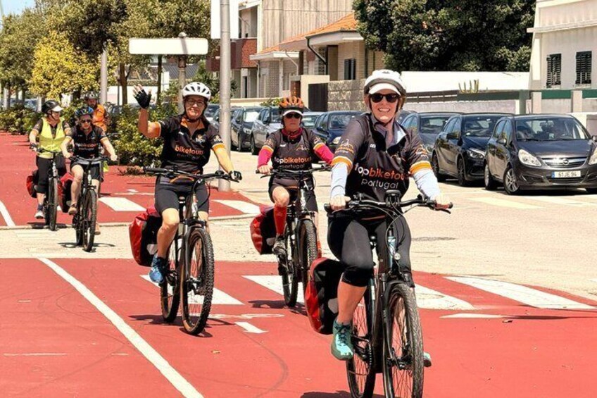 A group of cyclists on a red bike lane with buildings and parked cars in the background. 4