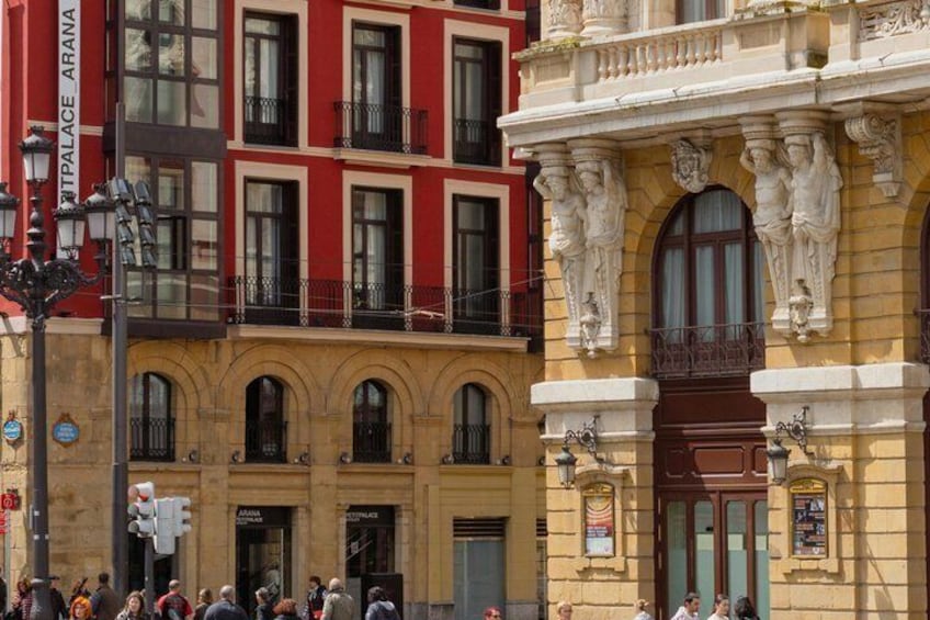 A street with historic buildings, a traffic light, and pedestrians. 4