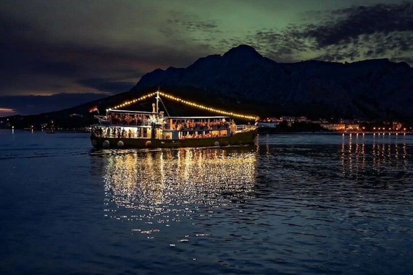 A boat with lights on a body of water with mountains in the background. 5