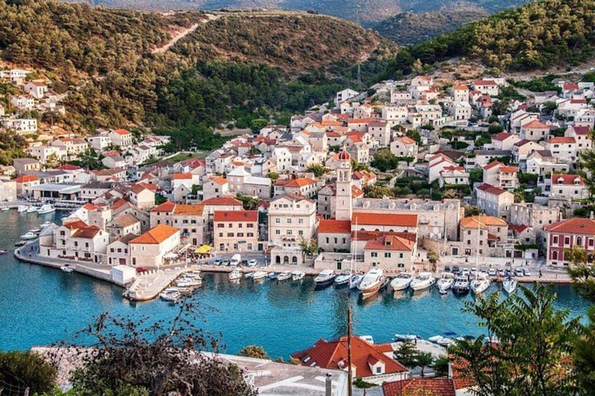 A coastal town with a marina, buildings with red roofs, and a hilly backdrop. 3