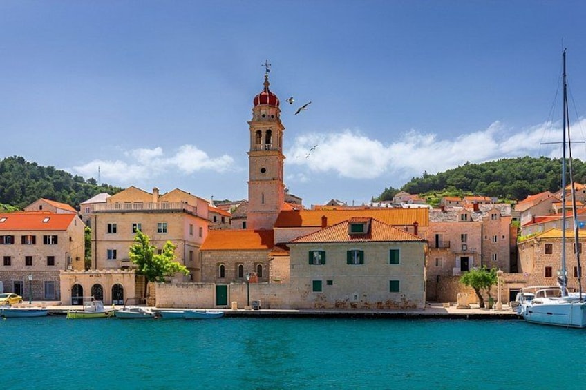 A coastal town with a prominent tower, waterfront buildings, and boats docked at the harbor. 2