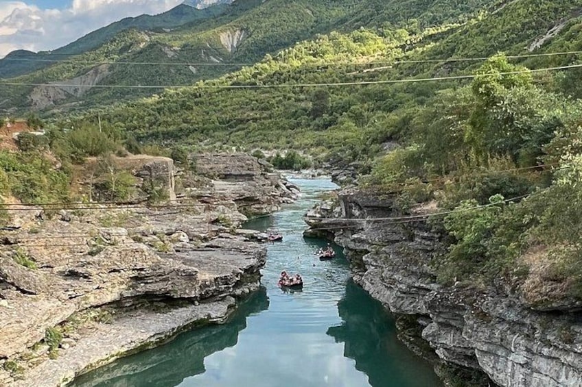 A river flowing through a rocky canyon with a person paddling a kayak. 1