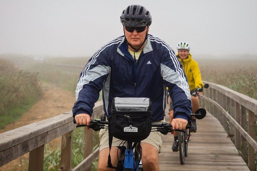 Two cyclists on a wooden bridge with a foggy background. 2