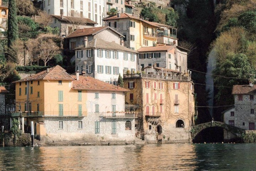 A river with buildings on stilts, a stone bridge, and a steep cliff. 1
