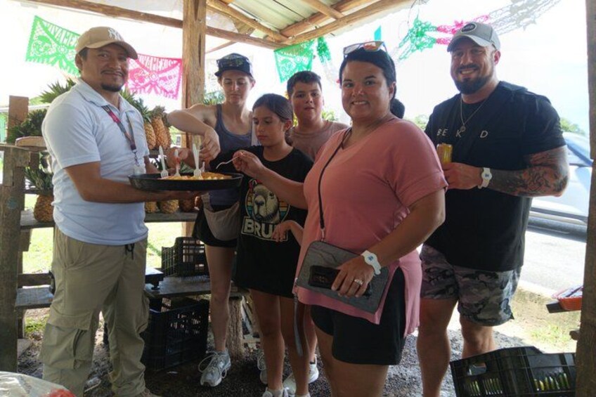 Un groupe de personnes participe à un événement en plein air, près d’un stand de nourriture, dans un espace abrité et décoré. 3
