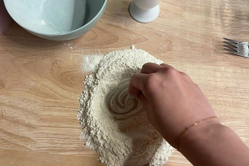 A hand mixing flour on a wooden surface. 5