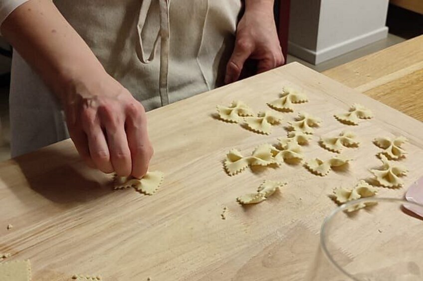 A person cutting pasta on a wooden cutting board. 2