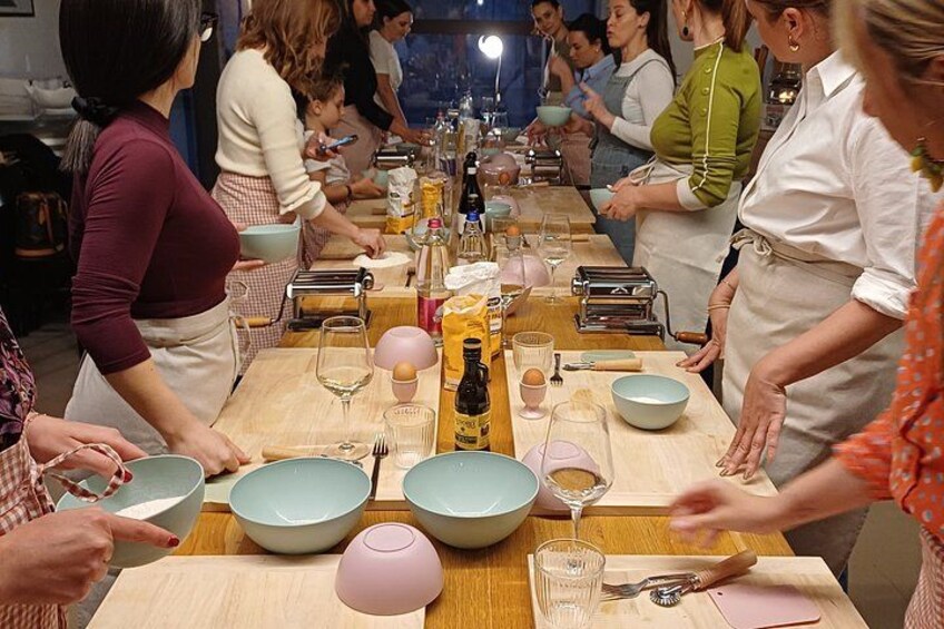 A group of people gathered around a long wooden table with bowls, bottles, and utensils. 3