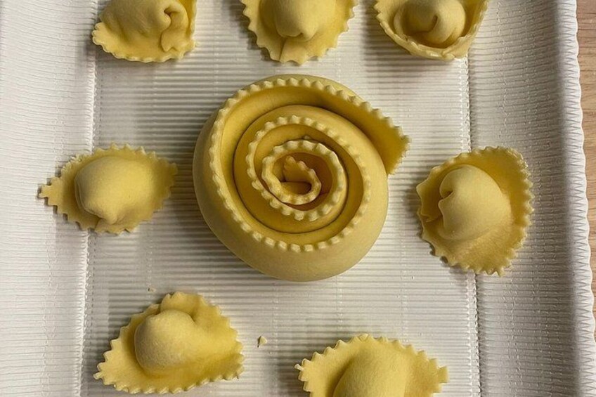 A tray of ravioli with a central spiral design, surrounded by plain ravioli. 4