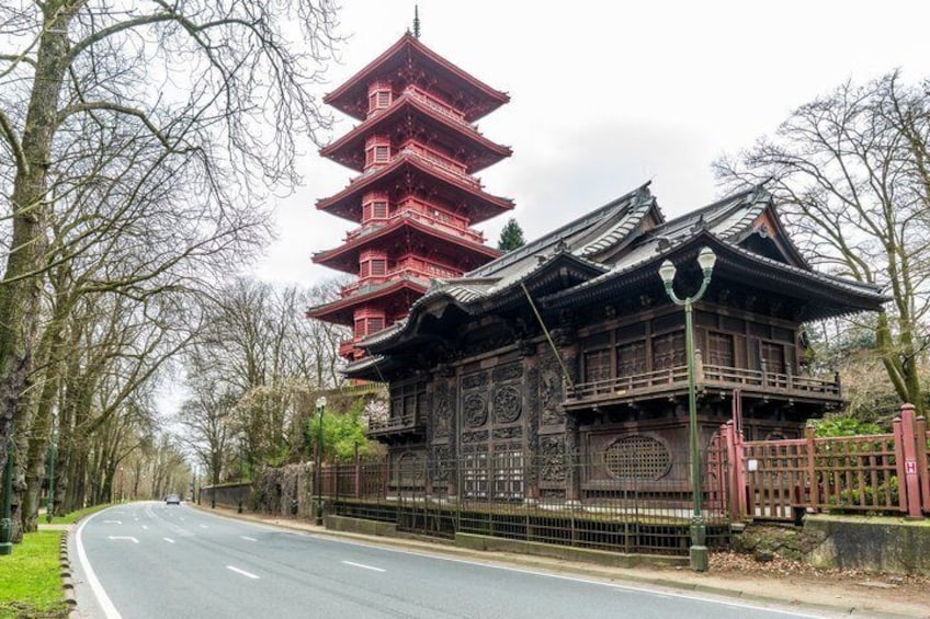 A traditional Japanese pagoda with a red spire, surrounded by a fence and trees. 2