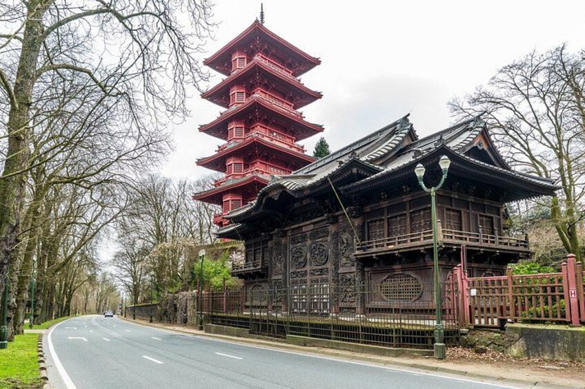 A traditional Japanese pagoda with multiple tiers, a wooden building with intricate carvings, and a road with a fence on the side. 3
