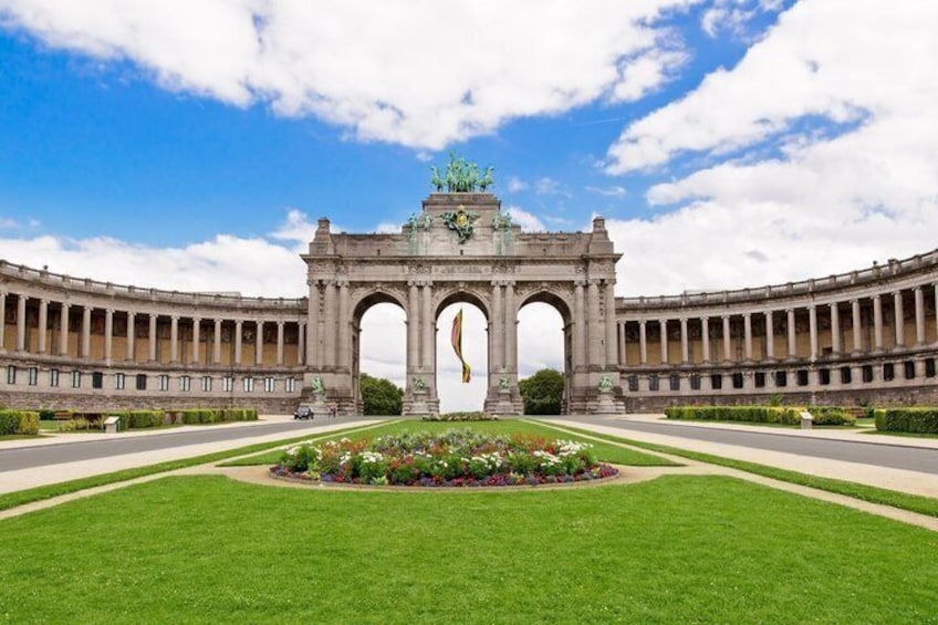 A grand archway with a central statue, surrounded by a well-maintained lawn and a circular flower bed. 1