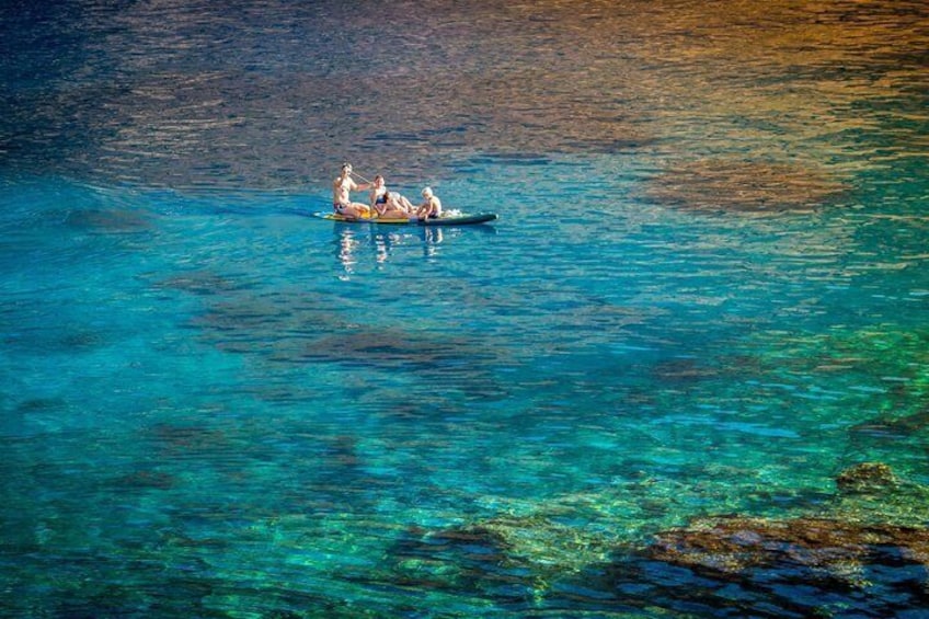 A group of people on a small boat in clear blue water. 2