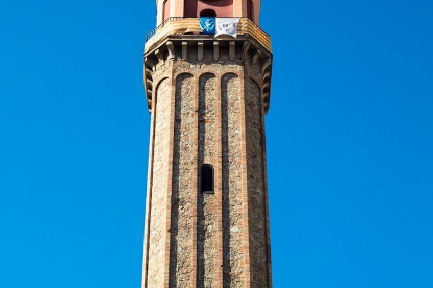Un'alta torre con un quadrante dell'orologio e uno stendardo blu. 1