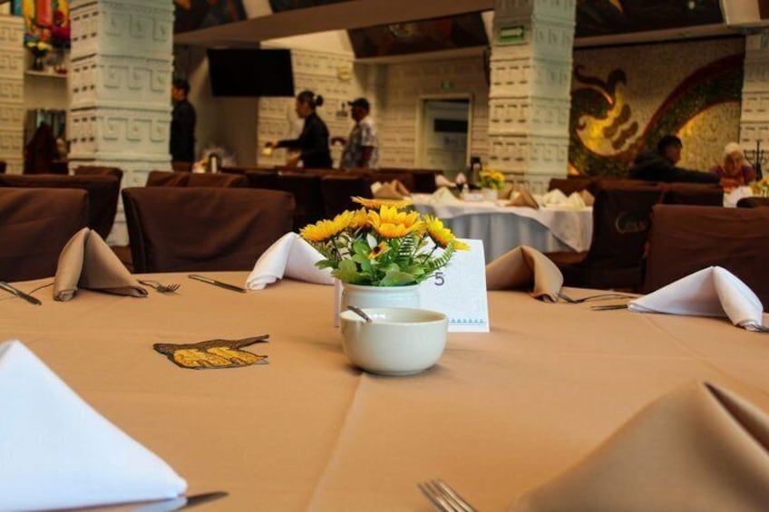 Ett restaurangbord med en vas med gula blommor, en meny och en servett. 4