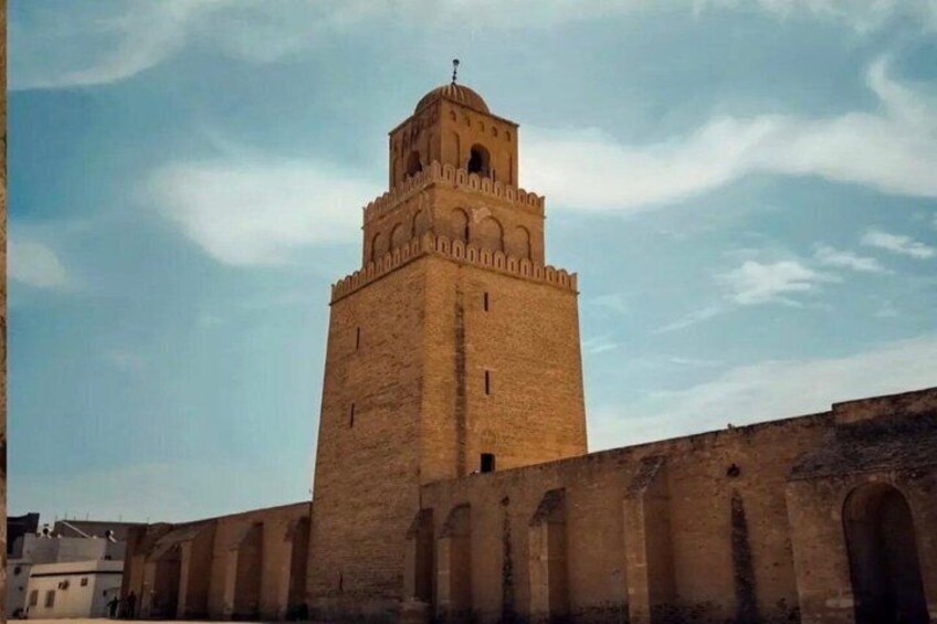 A tall, historic tower with arched windows and a crenellated top, set against a clear sky. 2