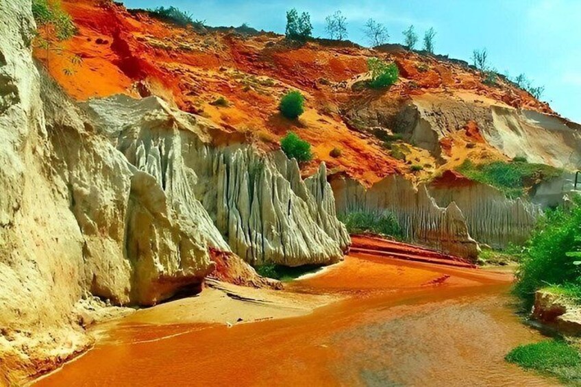 Un fiume con acqua rossa che scorre attraverso un canyon con formazioni rocciose rosse e bianche. 4