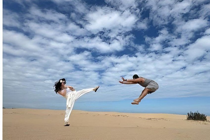 A person performing a martial arts kick in a desert landscape with a clear sky. 3