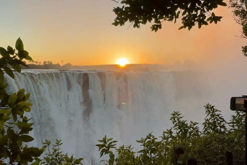 Ein Wasserfall mit untergehendem Sonnenuntergang im Hintergrund. 3