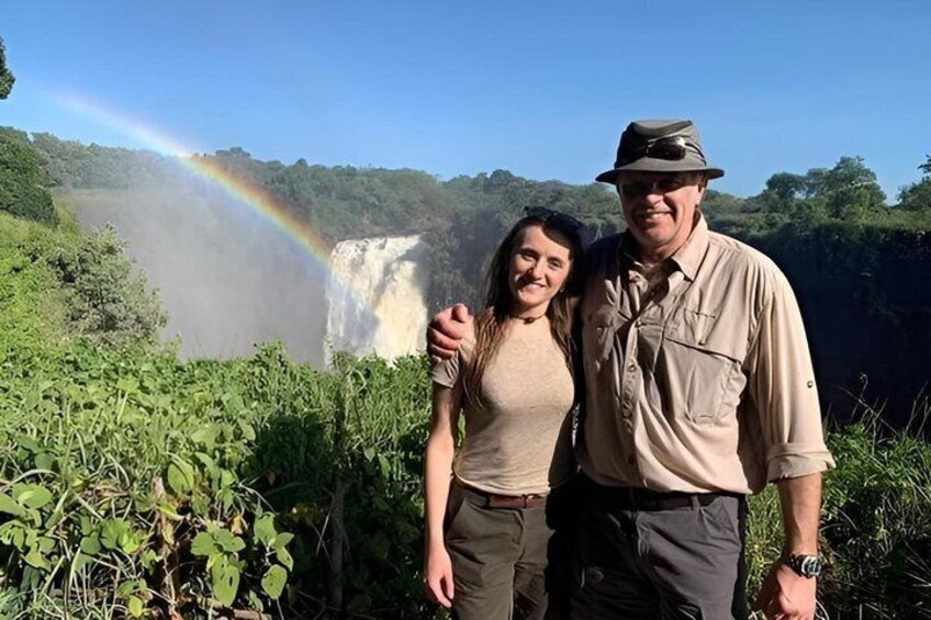 Ein Wasserfall mit Regenbogen, umgeben von viel Grün. 5