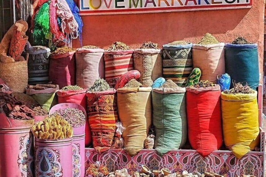 Un colorido despliegue de sacos llenos de diversas especias y hierbas, exhibido frente a una tienda llamada 'LOVE MARRAKEH'. 5