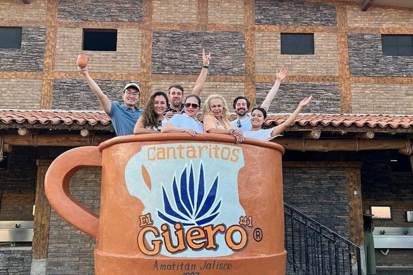 Un gruppo di persone su una grande struttura a forma di mug con la scritta 'cantarios El Guero' e 'Amatitan Jalisco'. 2