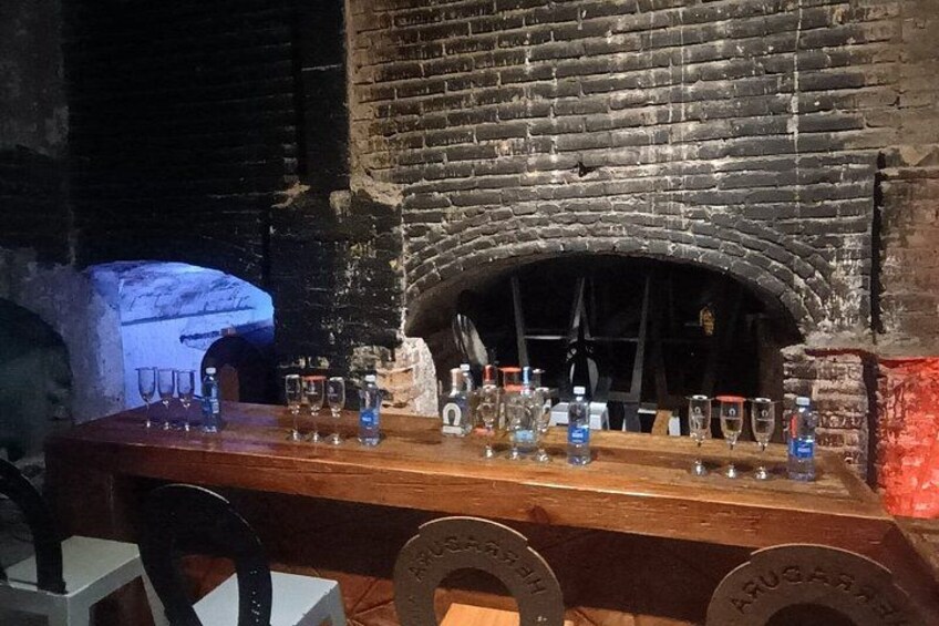 Un bar con bicchieri e bottiglie, un camino in mattoni e un tavolo di legno. 3