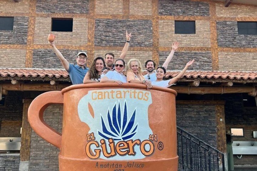 Un grupo de personas sobre una gran estructura con forma de jarra, donde se lee 'cantarios El Guero' y 'Amatitan Jalisco'. 2