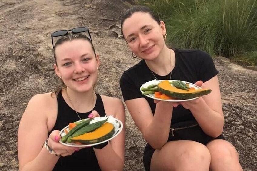 Two individuals holding plates with food, sitting outdoors. 3