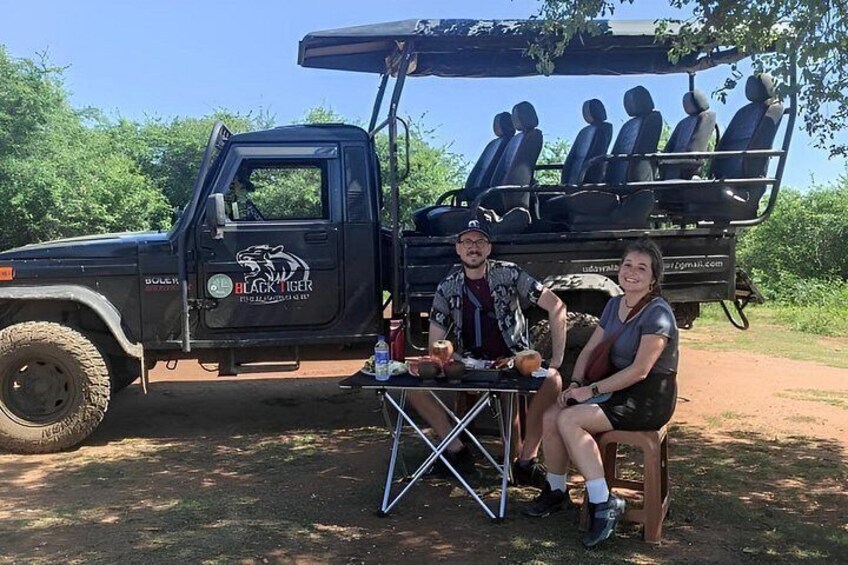 A black SUV with a logo and text on the side, a table with drinks, and a person sitting on a chair. 2