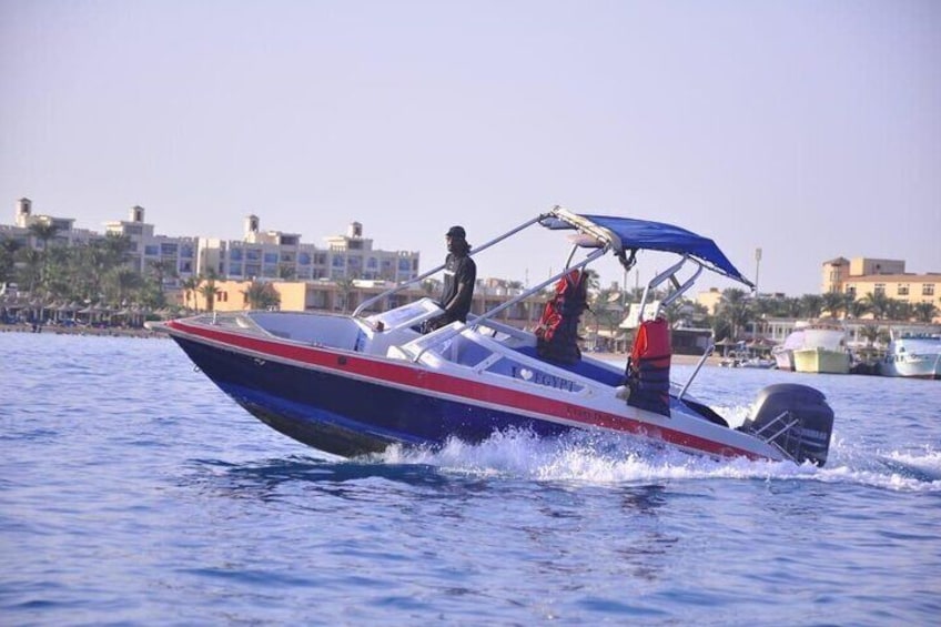 Een speedboot met een blauw dak, rode en witte strepen, en een bestuurder. 1
